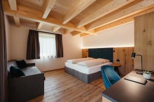 um quarto de hotel com uma cama e um sofá em Aria de Munt em San Vigilio Di Marebbe