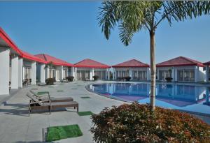 un complejo con una piscina con un banco y una palmera en Mannat Resort Paota, en Prāgpura