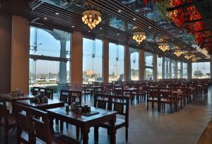 a restaurant with wooden tables and chairs and windows at Mannat Resort Paota in Prāgpura