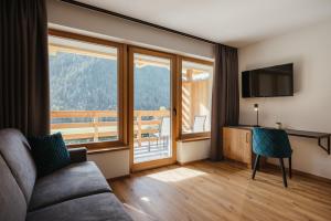 a living room with a couch and a large window at Aria de Munt in San Vigilio Di Marebbe