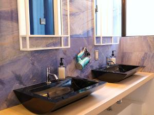 łazienka z 2 czarnymi umywalkami na ladzie w obiekcie 宮古島 Guesthouse Re-Spect w mieście Miyako-jima