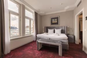 a bedroom with a bed with a bench and windows at Grand Hotel Amrâth Kurhaus The Hague Scheveningen in Scheveningen