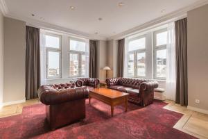 a living room with leather furniture and large windows at Grand Hotel Amrâth Kurhaus The Hague Scheveningen in Scheveningen