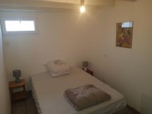 een kleine kamer met een wit bed en een raam bij Belle petite maison neuve avec jardin privatif in Longeville-sur-Mer