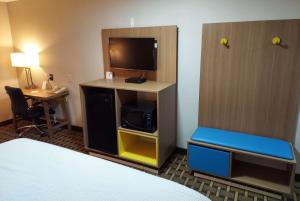 a hotel room with a bed and a tv and a desk at Days Inn & Suites by Wyndham Huntsville in Huntsville