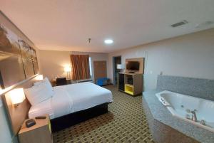 a hotel room with a bed and a bath tub at Days Inn & Suites by Wyndham Huntsville in Huntsville