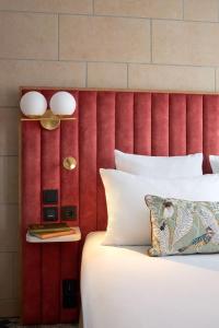 a bed with a red headboard with a white pillow and a table at Best Western Saint-Louis - Grand Paris - Vincennes in Vincennes