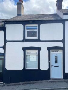 a white house with two windows and a door at Mount Cottage in Conwy