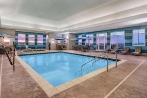a pool in a hotel with tables and chairs at Hawthorn Suites by Wyndham Dickinson in Dickinson