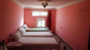 a room with four beds in a room with red walls at Hôtel Restaurant BOUGAFER in Oulad Akkou