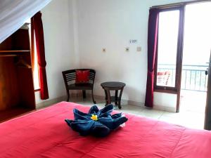 Un dormitorio con una cama roja con una flor. en One Homestay and Warung, en Munduk
