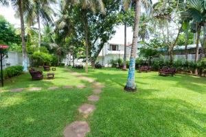 a park with benches and palm trees in a yard at Shelter Beach Resort in Mahabalipuram