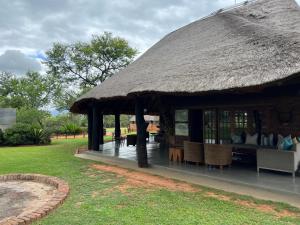 a hut with a thatched roof and chairs in a yard at Vilagama Game Lodge in Naboomspruit