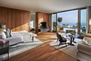 a bedroom with a large bed and a living room at Mandarin Oriental, Bodrum in Golturkbuku