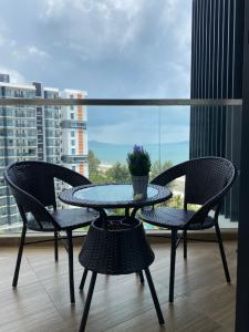 una mesa y sillas en un balcón con ventana en Timurbay Residence with Seaview 6pax 2Bedrooms Level 9 Kuantan, en Kampung Sungai Karang
