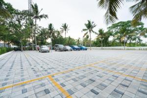 a parking lot with parked cars and palm trees at Shelter Beach Resort in Mahabalipuram
