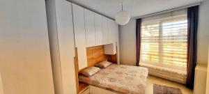 a small bedroom with a bed and a window at Sunflower Apartments in Pristina