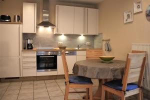 a kitchen with a table and chairs and a kitchen with white cabinets at Robby1 in Kaltenhof