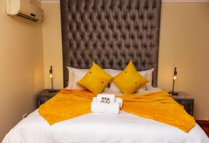 ein Schlafzimmer mit einem großen Bett mit gelber Bettwäsche und gelben Kissen in der Unterkunft CONSTANTIA GUEST LODGE in Pretoria