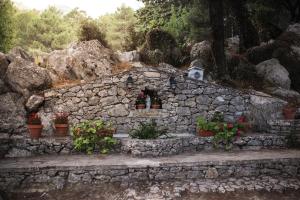 una pared de piedra con macetas de flores y un pequeño edificio en Camping TajoRodillo, en Grazalema