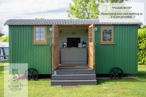 un cobertizo verde con puerta y porche en Glamping at South Lytchett Manor en Poole