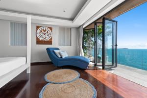 a living room with a blue couch and a view of the ocean at Villa Samayra - Super Luxury Villa Koh Samui in Chaweng