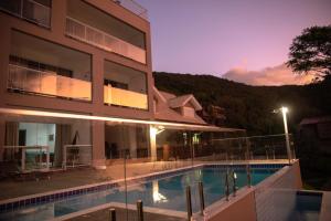 a hotel with a swimming pool in front of a building at Paraíso da Enseada de Brito in Palhoça