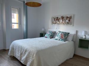 um quarto branco com uma cama branca e 2 almofadas em Apartamentos Turísticos LOS BARRUECOS em Cáceres