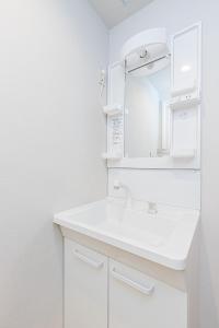 a white bathroom with a sink and a mirror at Mita Guest house - Vacation STAY 12100 in Tokyo