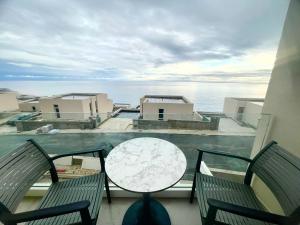 een balkon met 2 stoelen en een tafel en de oceaan bij AURA by DAMM's Villas in Llogara