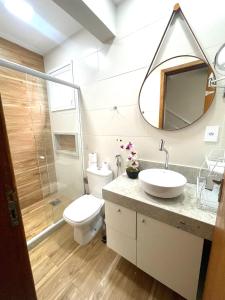 a bathroom with a sink and a toilet and a mirror at Cobertura Luxo com Jacuzzi Orla Praia Grande in Arraial do Cabo