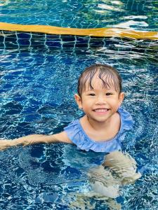 a young child is smiling in a swimming pool at Perennial Resort in Nai Yang Beach