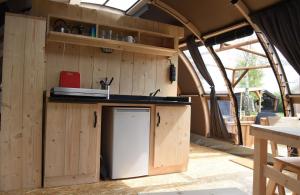 a kitchen in a caravan with a sink and a refrigerator at Panoramatent, in de natuur aan zee in Callantsoog