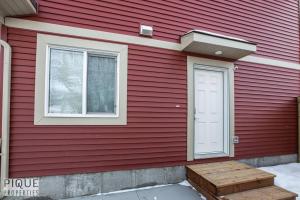 a red house with a white door and a window at NEW, Euro-Style Suite, Whyte Avenue, Netflix, Sleeps 6! in Edmonton