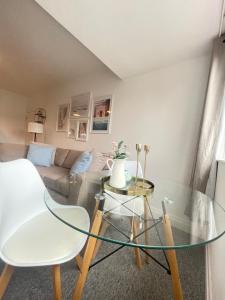 uma sala de estar com uma mesa de vidro e um sofá em Four Oaks em Bournemouth
