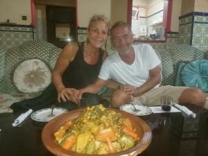 a man and woman sitting on a couch with a plate of food at Quiet House Tamraght in Agadir