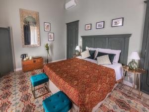 a bedroom with a large bed and two blue chairs at Donna Maddalena in Noto