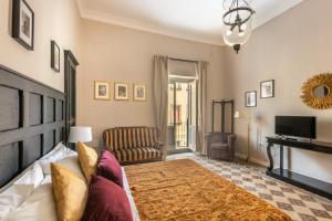 a bedroom with a bed and a couch and a television at Donna Maddalena in Noto