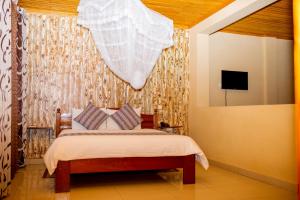 a bedroom with a bed with a window and a curtain at The Garden Place Hotel in Ruhengeri
