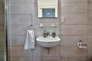 ein Badezimmer mit einem weißen Waschbecken und einem Spiegel in der Unterkunft Vallettastay Old Lodge Apartment 3 in Valletta