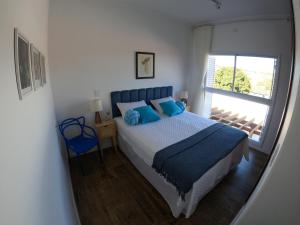 a bedroom with a bed with blue pillows and a window at Casa francesa de Piraju in Piraju