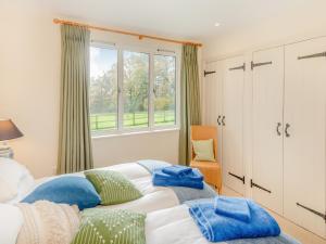 a bedroom with two beds and a window at Windover Barn in Slinfold