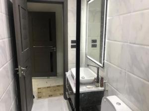 a bathroom with a toilet and a sink and a mirror at شقة فندقية بغرفتين قرب مول مصر وميدان جهينة families only in Sheikh Zayed