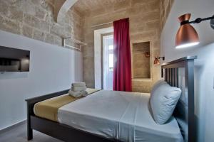 a bedroom with a large bed with a red curtain at Vallettastay Old Lodge Apartment 4 in Valletta