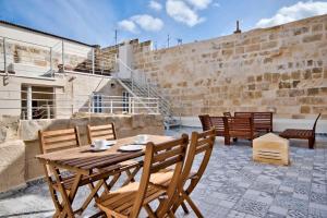 una mesa de madera y sillas en un patio en Vallettastay Old Lodge Apartment 4 en La Valeta