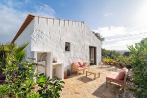 ein weißes Haus mit 2 Stühlen und einem Tisch in der Unterkunft Casa da Paz in Aljezur