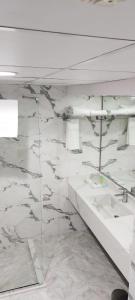baño con paredes de mármol blanco y lavabos blancos en Fortune Plaza Hotel, Dubai Airport en Dubái