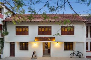 Cette maison blanche dispose de portes et de fenêtres en bois. dans l'établissement Niyati - Boutique Stay, à Cochin