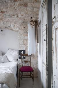 a bedroom with a bed and a chair and a brick wall at Trulli 18cinquantanove in Cisternino