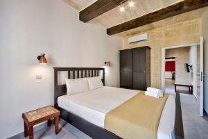 a bedroom with a large bed and a table at Vallettastay Old Lodge Apartment 7 in Valletta